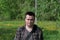 Portrait of a plump young man. On a spring meadow with bright green young grass and trees