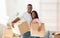 Portrait of positive black guy and his beauiful wife holding carton boxes, looking at camera and smiling on moving day