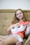 Portrait of Positive Caucasian Girl  With Injured Hand In Plaster Playing Hawaiian Guitar Indoors