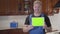 Portrait of positive caucasian man turning tablet with green screen to camera and smiling. Handyman standing at kitchen