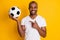 Portrait of positive cheerful afro american guy coach teach kids play football point index finger soccer ball wear