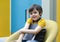 Portrait of Positive Child boy sitting on yellow chair holding his favorite book,  A happy school kid with smilig face enjoying