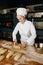 Portrait of positive female baker shaping bread bagels with seeds