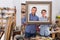 Portrait of positive guy and teen displaying frame in workshop