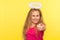 Portrait of positive happy little girl with long fair hair and angelic halo pointing finger, making choice