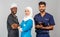 Portrait of positive healthcare workers standing in the hallway and looking at the camera. Group of paramedics smiling over gray