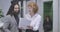 Portrait of positive middle aged Caucasian woman and young Middle Eastern man standing with paper and talking