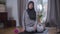 Portrait of positive Muslim woman in hijab posing in sportswear at home. Beautiful young woman looking at camera and