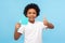 Portrait of positive nice preschool boy with curly hair showing thumbs up gesture and holding blue Like icon