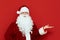 Portrait of positive santa claus isolated on red background shows his hand on a blank space and smiles. Funny Santa stands on red