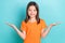 Portrait of positive schoolgirl dressed orange t-shirt palms demonstrate objects empty space isolated on turquoise color