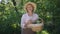 Portrait of positive senior female gardener posing with vegetable basket outdoors on sunny summer autumn day. Happy