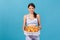 Portrait of positive sports woman holding cardboard box with fatty pizza, enjoying junk food after workout in gym, lack of