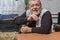 Portrait of positive Ukrainian peasant sitting at wooden table and telling funny story from his life