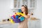 Portrait of positive young maid holding cleaning supplies at kitchen