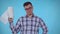 Portrait positive young man standing on a blue background and holding paper towels