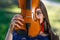 Portrait of a positive young woman. Part of the face is covered by the neck of the violin - image