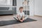 Portrait of practicing yoga, Boy child doing butterfly exercise on floor on a sports mat in home clothes: white t-shirt and pants.