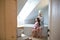 Portrait of pregnant woman with small daughter indoors in bathroom at home, brushing hair.