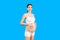Portrait of pregnant woman in underwear wearing elastic bandage against pain in the back at blue background with copy space.