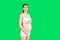 Portrait of pregnant woman in underwear wearing elastic bandage against pain in the back at green background with copy space.
