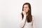 Portrait of preoccupied shocked young woman in light clothes looking aside, gnawing nails isolated on white wall