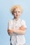 Portrait of preschool boy posing isolated over blue studio background.