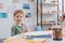 portrait of preschooler boy sitting at table with paper and colorful pencils for drawing