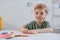 portrait of preschooler sitting at table with colorful pencils