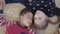 Portrait pretty african american boy and blond caucasian girl lying on the floor on the beige fluffy carpet and looking