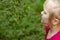 Portrait of pretty blond toddler girl sniffing blomming acacia flowers in a summer day