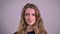 Portrait of pretty blonde caucasian young woman watching calmly into camera on gray background.