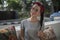 Portrait of a pretty brunette with a braid in a summer cafe near the road, beauty in a red rag front and stylish round