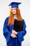 Portrait of pretty cheerful girl in gown and graduation cap