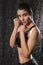 Portrait of pretty concentrated sportswoman doing kickboxing exercises and looking at camera posing under rain, isolated over