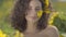 Portrait of pretty curly confident playful girl looking at the camera smiling standing on the sunflower field. Bright