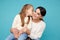 Portrait of pretty family of mother and daughter together in the blue studio. Kid kissing mom.