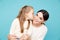 Portrait of pretty family of mother and daughter together in the blue studio. Kid kissing mom.