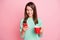 Portrait of pretty focused cheery girl drinking tea using device chatting isolated over pink pastel color background