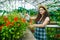 Portrait of pretty girl farmer using spray bottle in greenhouse watering flowers