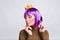 Portrait pretty girl with purple hairstyle in gold crown in studio. She looks peaceful, has violet tinsel on closed eyes