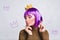 Portrait pretty girl with purple hairstyle in gold crown in studio. She looks peaceful, has violet tinsel on closed eyes