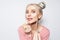 Portrait of pretty girl putting on lip gloss, on white studio background.