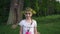 Portrait of pretty little girl with wreath on the head smiling into camera. Steadycam flying around girl.