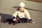 Portrait of pretty little teenager child girl sitting in white helmet, inline skates and safety equipment