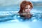 Portrait of pretty sexy, seductive, sensual happy smiling redhead woman, relaxes swimming in turquoise, blue thermal bath hot