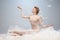 Portrait of pretty, slim beautiful young girl, graceful ballerina in image of angel with wings sitting on cloud isolated