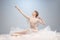 Portrait of pretty, slim beautiful young girl, graceful ballerina in image of angel with wings sitting on cloud isolated