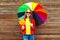 Portrait pretty smiling woman with colorful umbrella in autumn with maple leafs over wooden background wearing red leather jacket