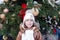 Portrait of pretty toddler girl on background of a huge Christmas tree on the winter Christmas fair